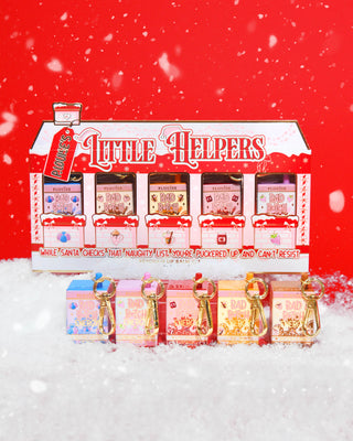 Christmas-themed Little Helpers Lip Balm Gift Set packaging on a red background surrounded by snow