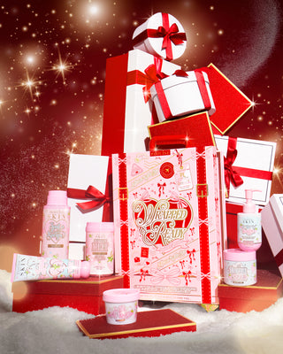 Pink P.Louise Wrapped & Ready body care package with a festive design surrounded by christmas gift boxes on a red background and cosmetic products