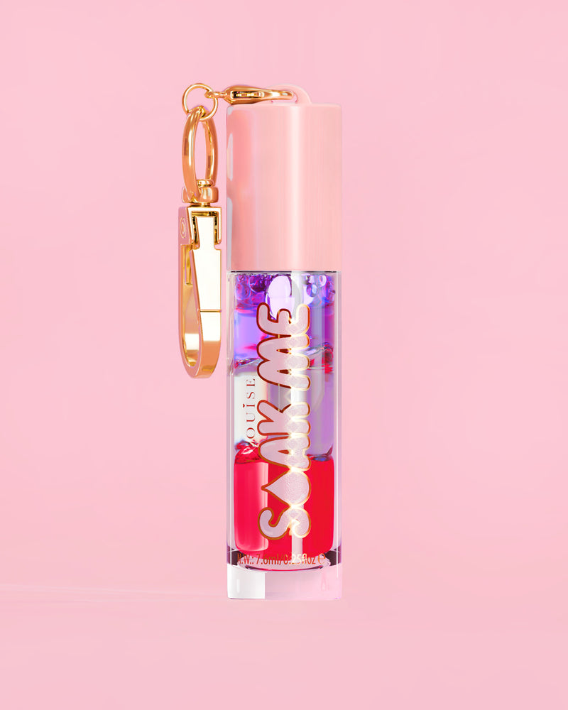 P. Louise Soak Me Lip Oil met kleurrijke gelaagde olie in een roze tube met gouden sluiting op een roze achtergrond