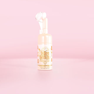 Een fles op de P.Louise In Love With Me schuimende gezichtswas in kokoscakegeur tegen een roze achtergrond