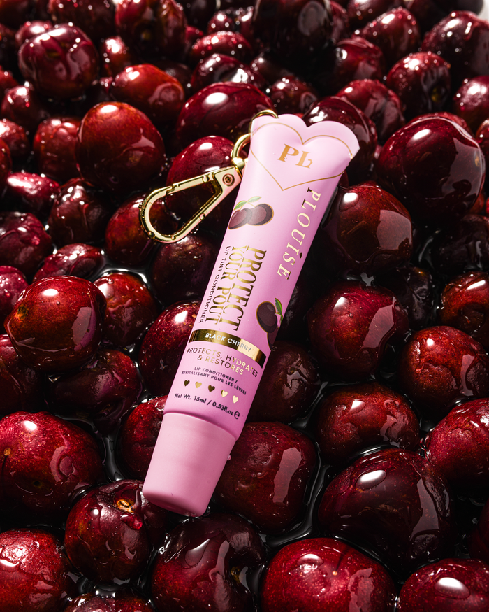 Roze zwarte kersengeur getinte bescherm je lippenbalsem met gouden clip op een bedje van kersen