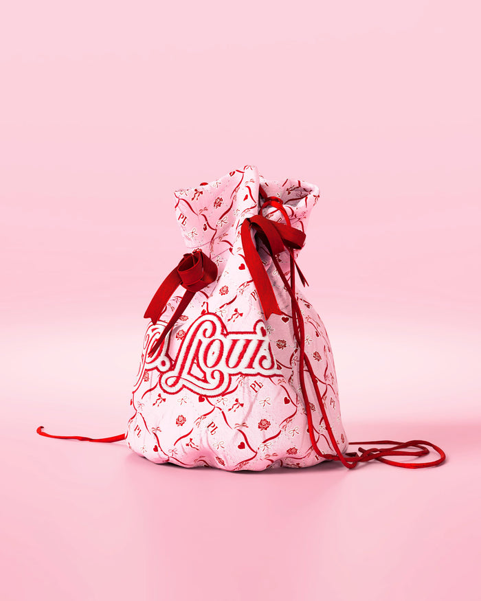 Roze tasje met trekkoord met rode strikken en een feestelijk design met 'P.Louis' branding op een roze achtergrond