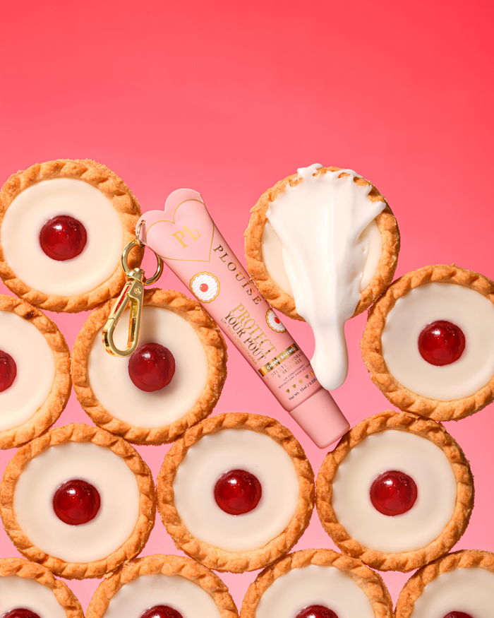 Getinte roze kersen-amandelgeur beschermt je lippenbalsem met een gouden clip tussen kersen-bakewell-desserts
