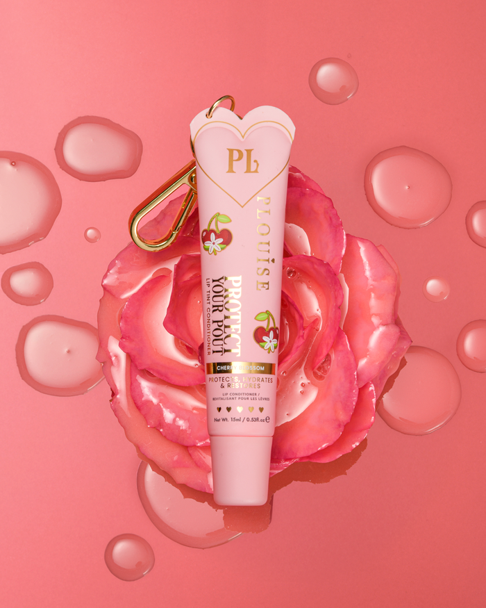 Roze naar kersenbloesem geurende getinte bescherm je pruillipconditioner met gouden clip bovenop een roze bloem