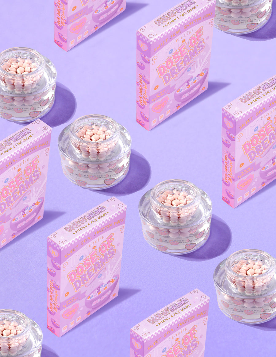 Doorzichtige containers met P.Louise DOse of Dreams Viatmin C Capsule Face Cream met roze capsule erin omgeven door roze ontbijtgranendozen op een paarse achtergrond