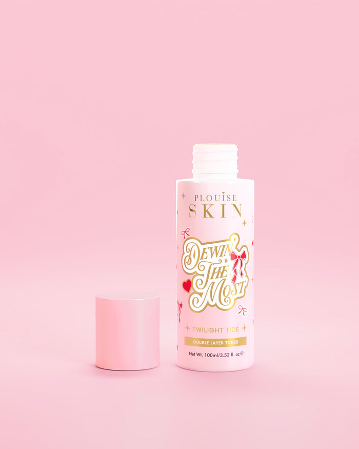 Roze fles P.Louise Dewin The MOst Double Layer Toner met rode strikjes tegen een roze achtergrond 