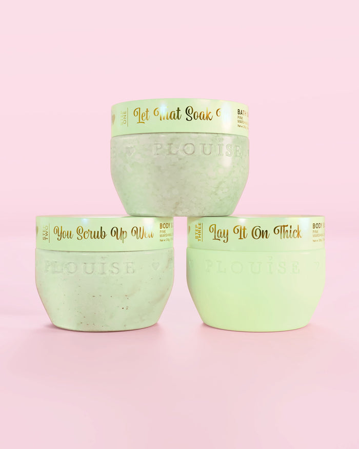 Drie P.Louise Hop Into Self-Care chocolade bedekte aardbeien groene containers met badzout, bodyscrub en body butter met gouden tekst op een roze achtergrond