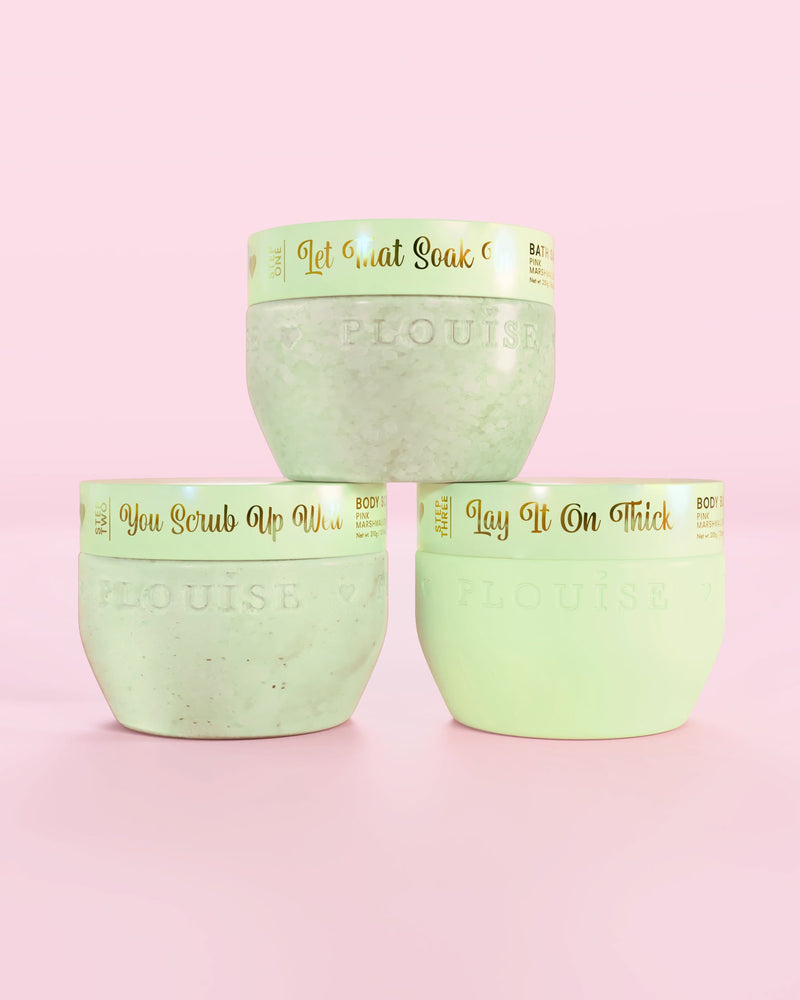 Drie P.Louise Hop Into Self-Care chocolade bedekte aardbeien groene containers met badzout, bodyscrub en body butter met gouden tekst op een roze achtergrond