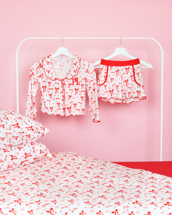 Set roze en wit gestreepte meisjes P.Louise kerstpyjama's met strik op hangers in een roze slaapkamer met bijpassend beddengoed 