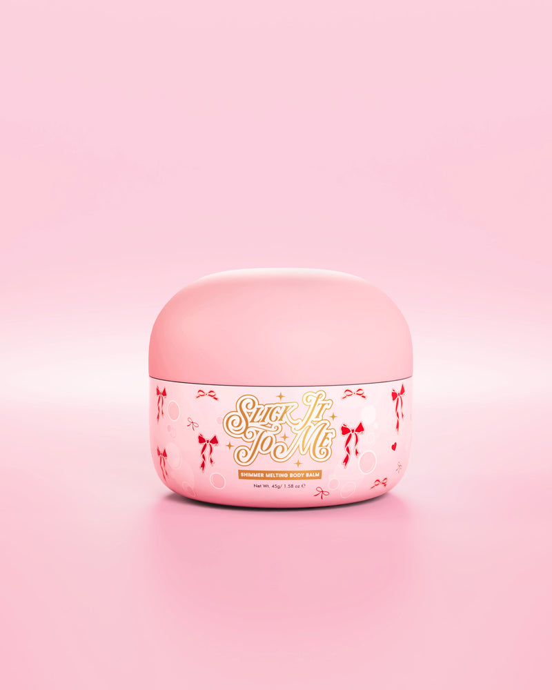 Roze potje SLick It To Me glinsterende smeltende lichaamsbalsem met decoratieve rode strikelementen op een roze achtergrond
