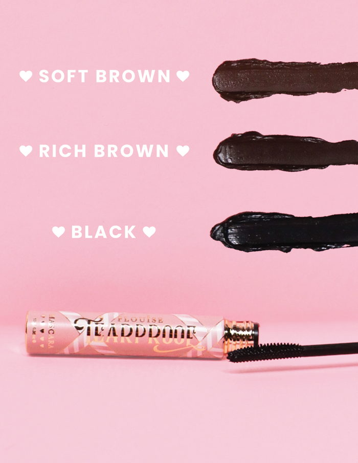 De P. Louise Tearproof Mascara-stalen in drie verschillende tinten met de tekst voor elke tint op een roze achtergrond