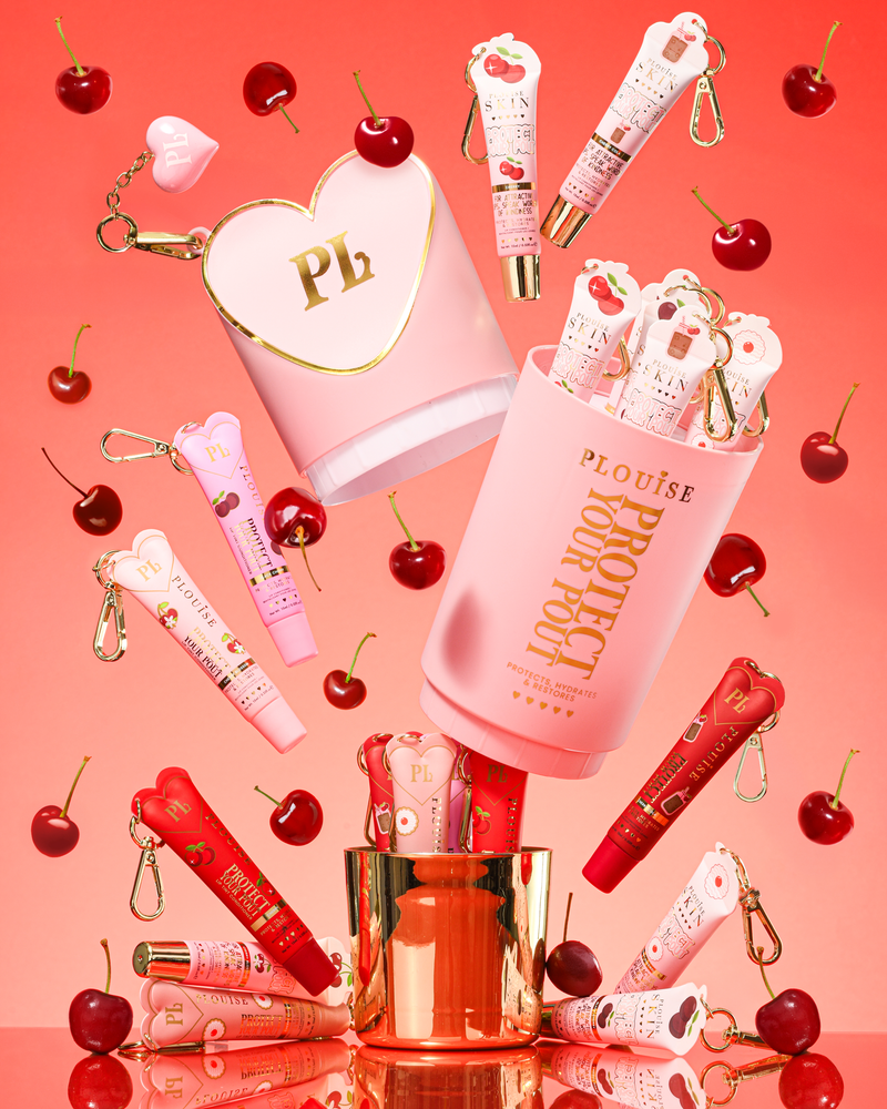 Roze XL Protect Your Pout-cadeauset die is geopend, omringd door kersen en roze en rode lipconditioners op een roze achtergrond