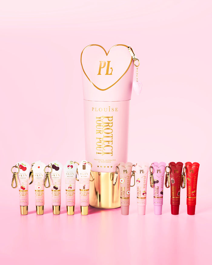 Een set lipconditioners met roze en rode kersengeur met prominent roze en goud beschermen je pruilflesje in het midden op een roze achtergrond.