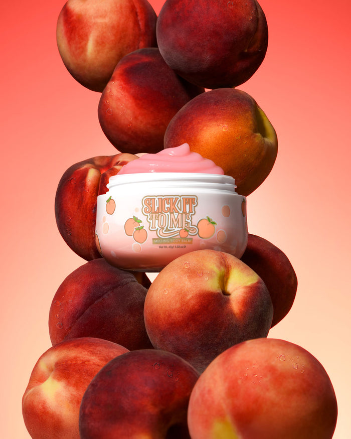 Pot P. Louise Slick It To Me Peach Melting Body Balm met roze crème omringd door perziken op een verloopachtergrond