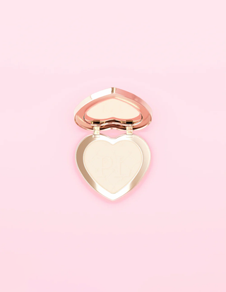 A heart-shaped P.Louise under-eye brightening and blurring pressed powder against a pink background
