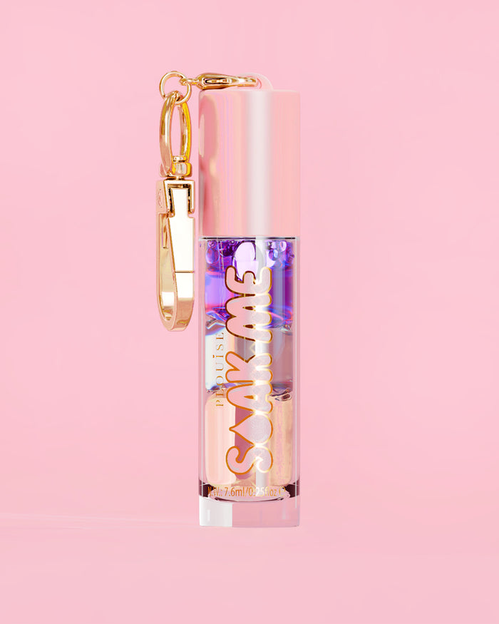 P. Louise Soak Me Lip Oil met kleurrijke gelaagde olie in een roze tube met gouden sluiting op een roze achtergrond