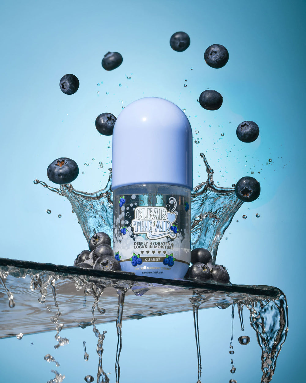 Fles P. Louise Clear The Air Blueberry Gel Cleanserl omgeven door bosbessen en waterspatten op een blauwe achtergrond
