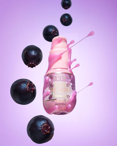 Flacon rose de sérum correcteur de taches brunes P. Louise Erase The Trace avec du liquide sortant du flacon entouré de cassis sur fond violet