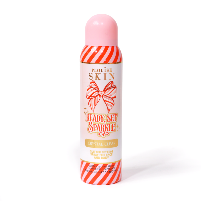 Een fles P. Louise Ready Set Sparkle Christmas Glitter Setting Spray met rode en roze strepen op de fles en een rood en roze gestreepte strik tegen een witte achtergrond