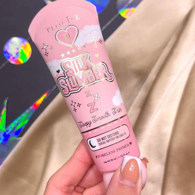 Une personne tenant un tube de P.Louise Silk Slumber Poreless Primer avec un fond rose et des détails sur le produit cosmétique.