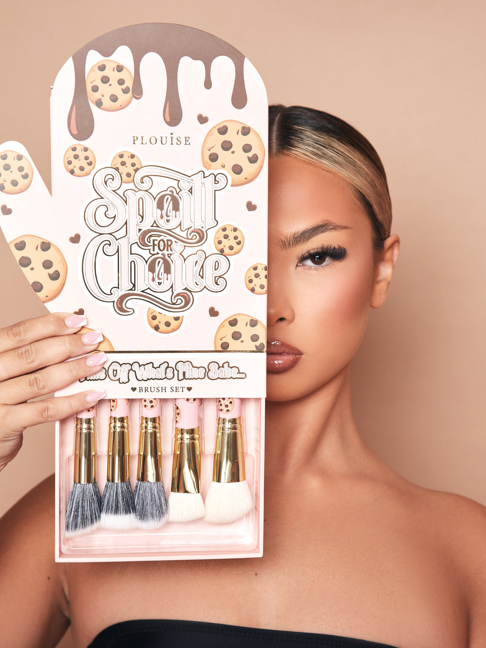 Une image de l'ensemble de pinceaux de maquillage 5 pièces Spoiled For Choice de P.Louise dans une boîte d'emballage de gants de cuisine avec un plateau retiré sur le fond montrant partiellement les pinceaux. L'emballage montre le visage d'un demi-modèle maquillé
