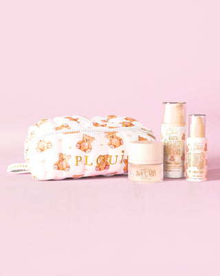 Een afbeelding van de P.Louise Softest Touch Skincare Starter Kit met een grote print teddybeer make-up- en huidverzorgingstas en 3 huidverzorgingsproducten tegen een roze achtergrond