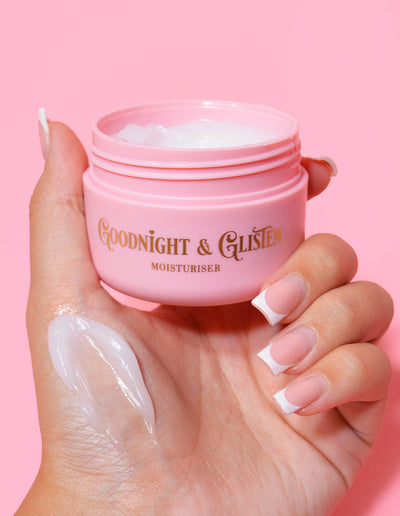 Une main tenant un pot rose de gel hydratant P.Louise Goodnight & Glisten avec un peu de crème hydratante visible sur le .et